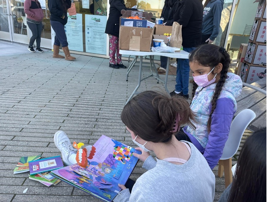 Emma Casaudoumecq 24 shares reading materials with children at a KIP event. Her junior fellowship aimed at boosting early childhood literacy in underserved communities. Courtesy of Emma Casaudoumecq